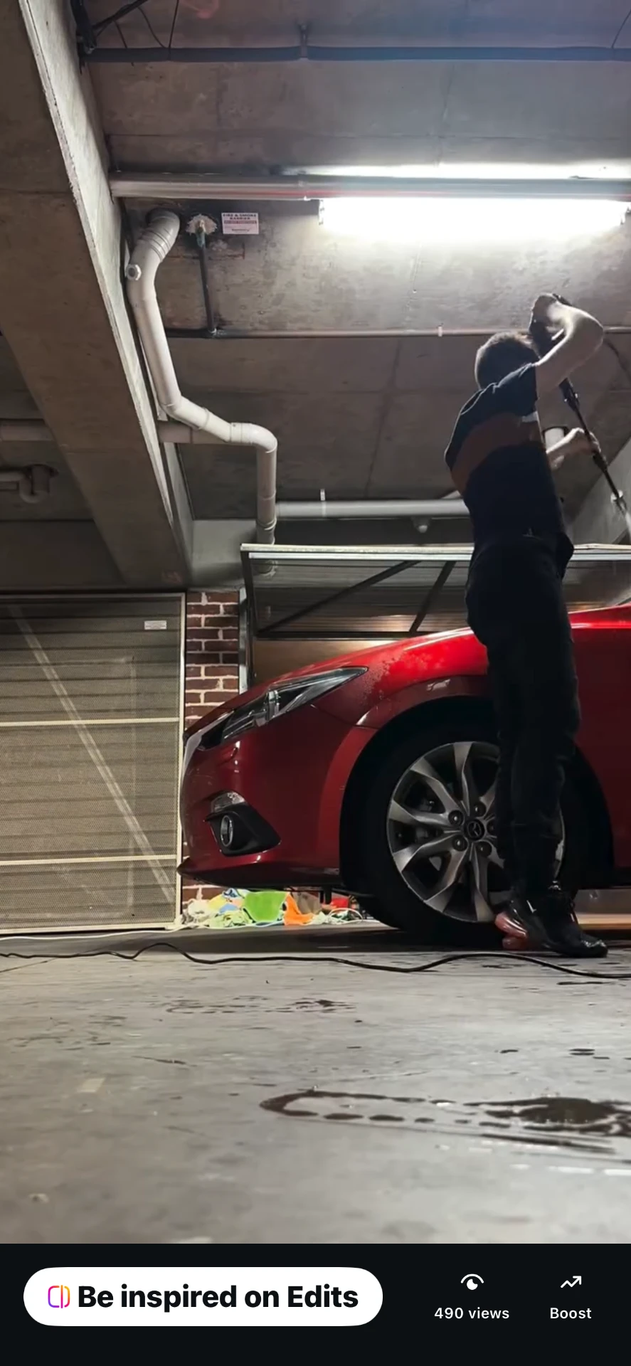 James, the detailer behind Detail Xpress, pressure washing a red car at a customer's location